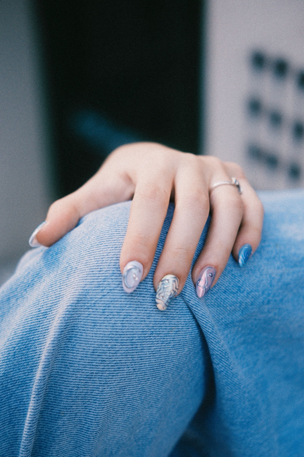 Artistic hand-painted nail set styled against a denim background