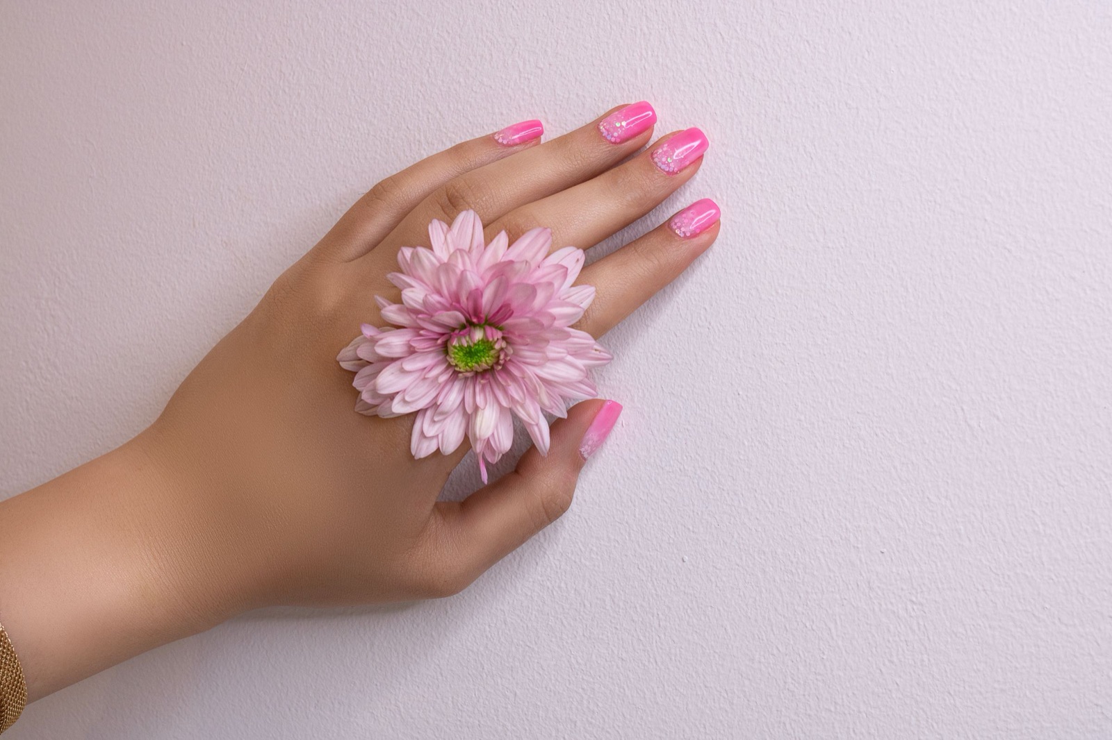 Soft floral hand-painted nail design held next to a pink flower