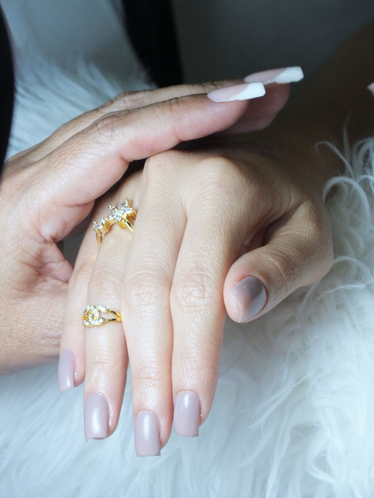 Neutral manicure styled with layered gold jewellery on both hands