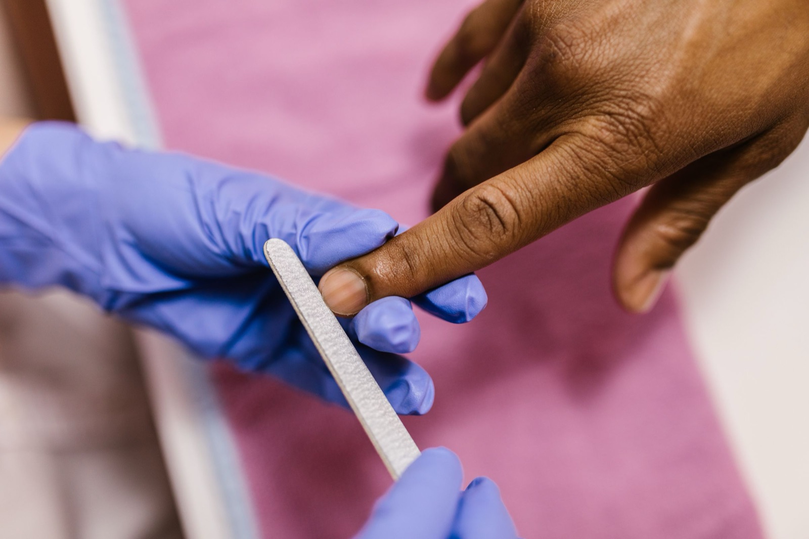 Nail technician filing and repairing a single broken nail at a Berkeley nail studio