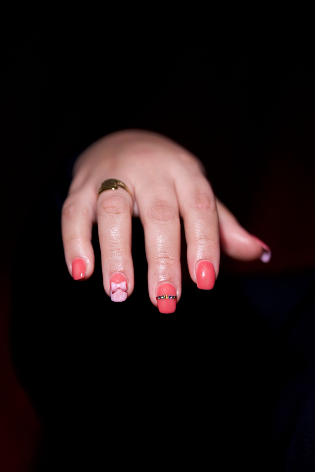 Pink hand-painted nail art styled with a gold ring on shaped gel nails